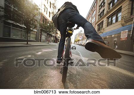 Caucasian man riding bicycle on urban street View Large Photo Image Stock Image - Caucasian man riding bicycle on urban street. Fotosearch