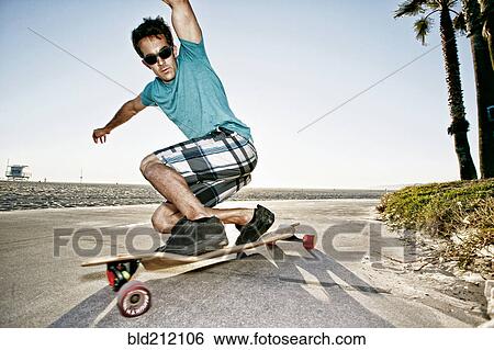 Caucasian man riding longboard on beach View Large Photo Image Stock Photograph - Caucasian man riding longboard on beach. Fotosearch