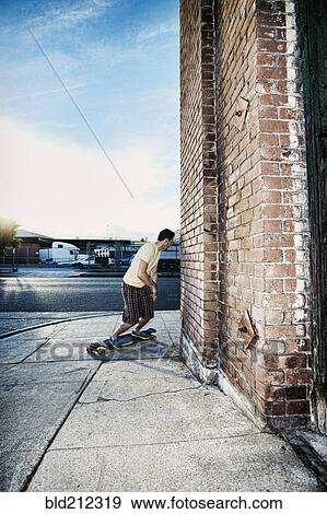 Stock Photo - Caucasian man riding skateboard on city street. Fotosearch