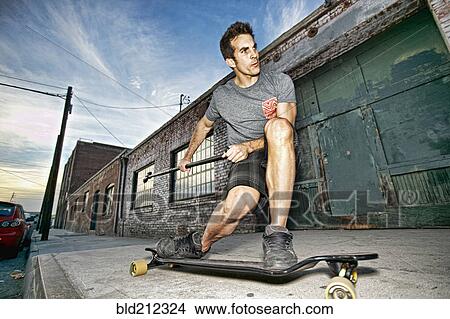 Caucasian man riding skateboard with land paddle View Large Photo Image Picture - Caucasian man riding skateboard with land paddle. Fotosearch