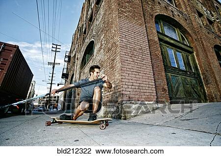 Caucasian man riding skateboard with land paddle View Large Photo Image Stock Image - Caucasian man riding skateboard with land paddle. Fotosearch