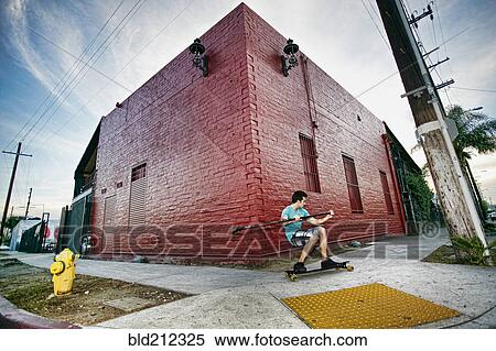Stock Photography - Caucasian man riding skateboard with land paddle. Fotosearch