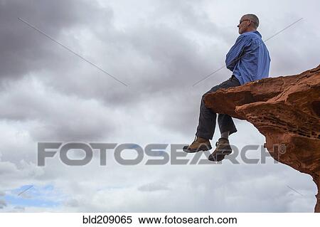 Caucasian man sitting on cliff edge View Large Photo Image Stock Photography - Caucasian man sitting on cliff edge. Fotosearch