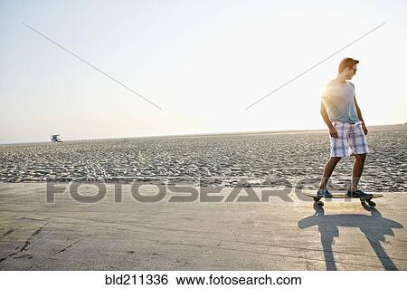 Stock Photograph - Caucasian man skating on beach. Fotosearch