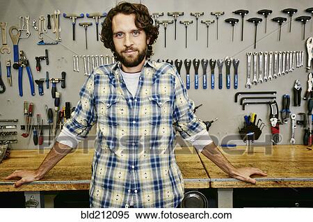 Stock Photography - Caucasian man smiling in bicycle repair shop. Fotosearch