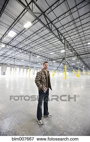 Caucasian man standing in empty warehouse View Large Photo Image Stock Photo - Caucasian man standing in empty warehouse. Fotosearch