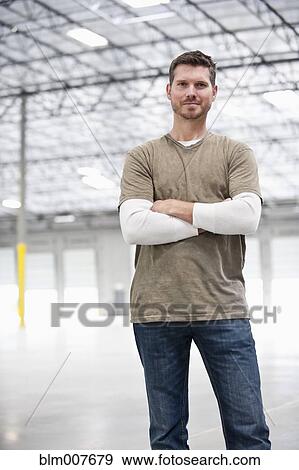 Stock Photo - Caucasian man standing in empty warehouse. Fotosearch