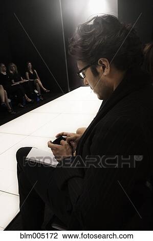 Caucasian man text messaging on cell phone during fashion show View Large Photo Image Stock Image - Caucasian man text messaging on cell phone during fashion show. Fotosearch