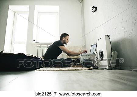 Caucasian man using laptop in bedroom View Large Photo Image Stock Photo - Caucasian man using laptop in bedroom. Fotosearch