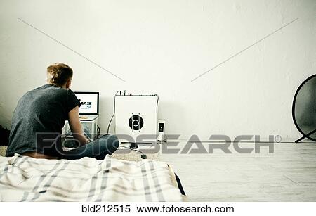 Caucasian man using laptop in bedroom View Large Photo Image Stock Photography - Caucasian man using laptop in bedroom. Fotosearch