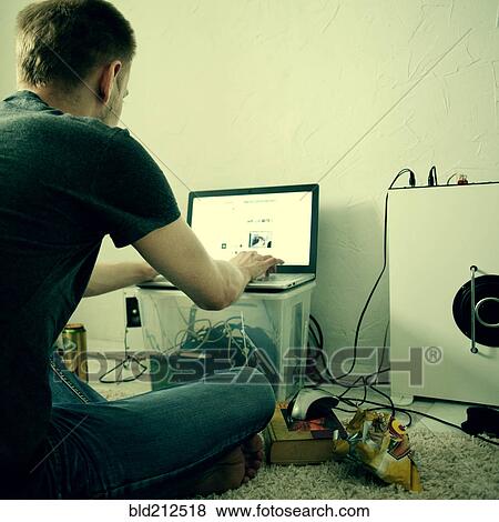 Stock Photo - Caucasian man using laptop on floor. Fotosearch