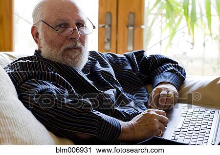 Caucasian man using laptop on sofa View Large Photo Image Stock Image - Caucasian man using laptop on sofa. Fotosearch