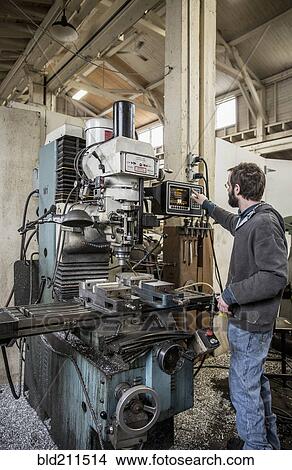 Picture - Caucasian man using machinery in metal shop. Fotosearch