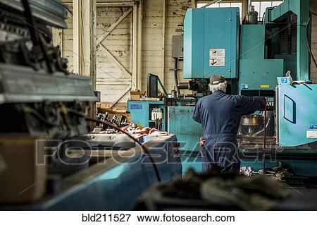 Stock Photo - Caucasian man using machinery in metal shop. Fotosearch