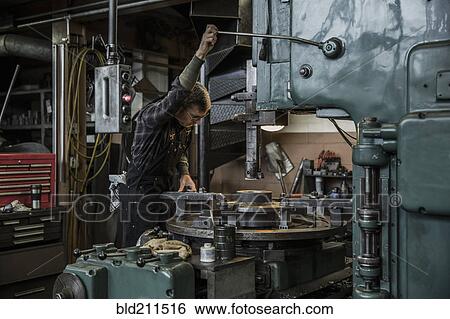 Stock Photograph - Caucasian man using machinery in metal shop. Fotosearch