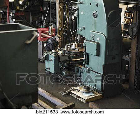Stock Image - Caucasian man using machinery in workshop. Fotosearch