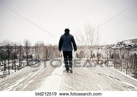 Caucasian man walking on snowy roof View Large Photo Image Stock Photo - Caucasian man walking on snowy roof. Fotosearch