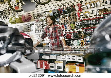 Stock Image - Caucasian man working in bicycle shop. Fotosearch
