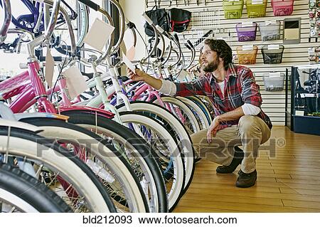 Stock Image - Caucasian man working in bicycle shop. Fotosearch