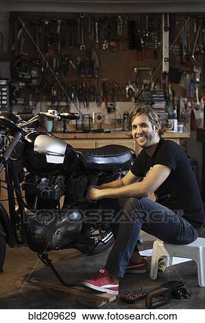 Stock Photo - Caucasian mechanic working on motorcycle. Fotosearch