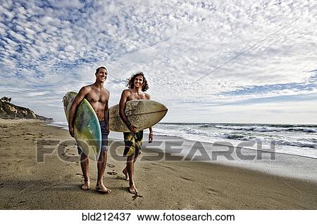 Caucasian men carrying surfboards on beach View Large Photo Image Stock Photo - Caucasian men carrying surfboards on beach. Fotosearch