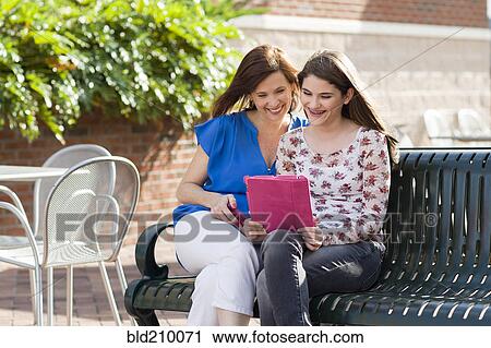 Stock Image - Caucasian mother and daughter using digital tablet. Fotosearch