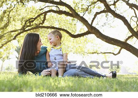 Stock Photograph - Caucasian mother and son relaxing in park. Fotosearch