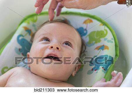 Stock Image - Caucasian mother bathing baby in tub. Fotosearch