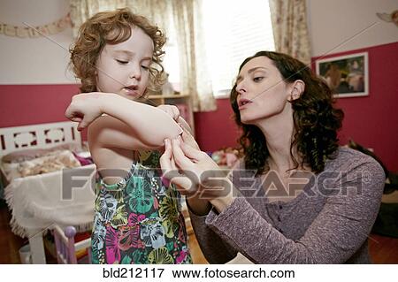 Stock Photo - Caucasian mother examining daughter's scrape. Fotosearch