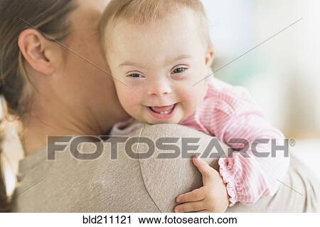 Stock Image - Caucasian mother holding baby girl with Down Syndrome. Fotosearch