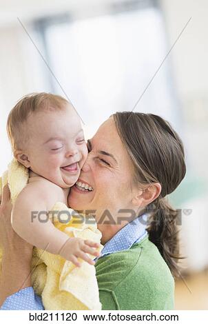 Stock Image - Caucasian mother playing with baby girl with Down Syndrome. Fotosearch
