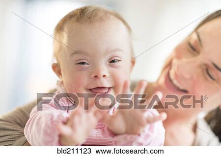 Stock Image - Caucasian mother playing with baby girl with Down Syndrome. Fotosearch