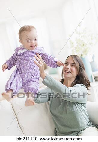 Stock Image - Caucasian mother playing with baby with Down Syndrome. Fotosearch