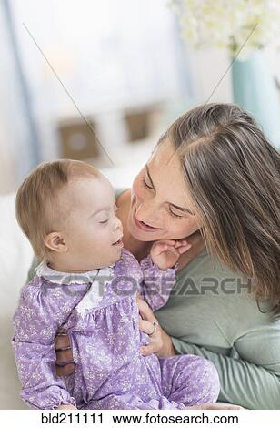 Stock Image - Caucasian mother playing with baby with Down Syndrome. Fotosearch