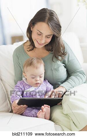Stock Photo - Caucasian mother reading to baby with Down Syndrome. Fotosearch