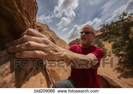 Stock Photograph - Caucasian rock climber scaling cliff. Fotosearch
