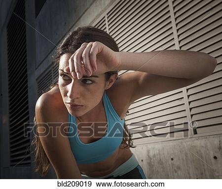 Stock Photo - Caucasian runner wiping sweat off forehead. Fotosearch
