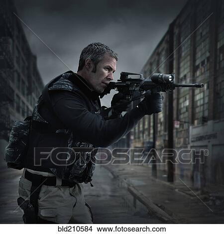 Picture - Caucasian sniper aiming gun on city street. Fotosearch