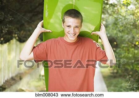 Caucasian teenage boy smiling and holding surfboard View Large Photo Image Stock Image - Caucasian teenage boy smiling and holding surfboard. Fotosearch