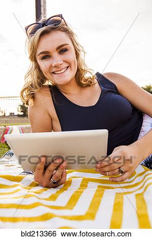 Stock Photograph - Caucasian teenage girl using tablet computer in park. Fotosearch