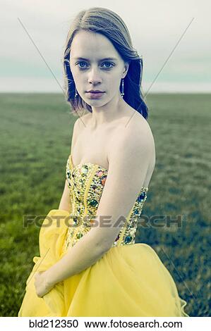 Stock Image - Caucasian teenage girl wearing gown in rural field. Fotosearch