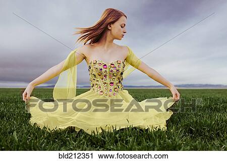 Stock Image - Caucasian teenage girl wearing gown in rural field. Fotosearch