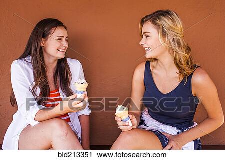 Stock Image - Caucasian teenage girls eating ice cream cones. Fotosearch