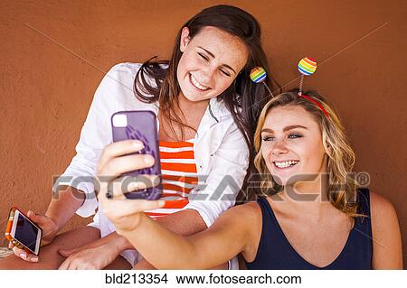 Picture - Caucasian teenage girls taking cell phone selfie. Fotosearch
