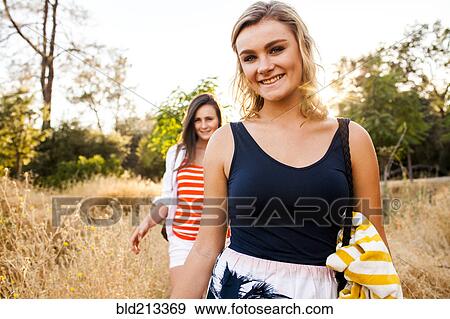 Stock Photo - Caucasian teenage girls walking in tall grass in field. Fotosearch