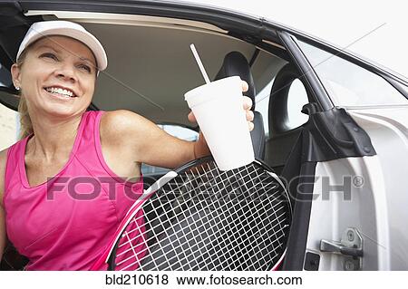 Stock Photo - Caucasian tennis player climbing out of car. Fotosearch