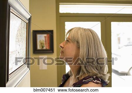 Caucasian woman admiring painting in gallery View Large Photo Image Stock Image - Caucasian woman admiring painting in gallery. Fotosearch