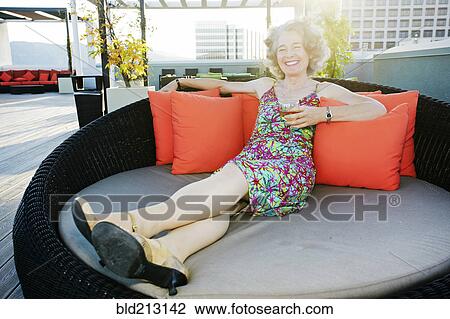 Stock Image - Caucasian woman drinking wine on urban rooftop. Fotosearch
