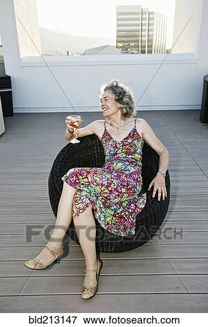 Stock Photo - Caucasian woman drinking wine on urban rooftop. Fotosearch