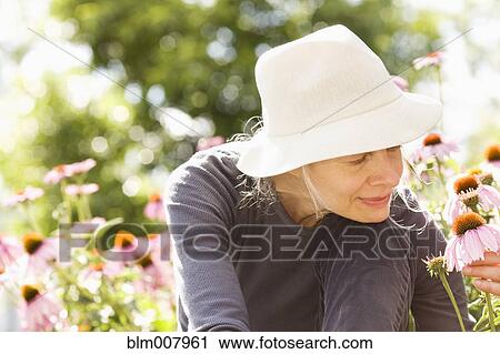Stock Image - Caucasian woman examining flowers. Fotosearch